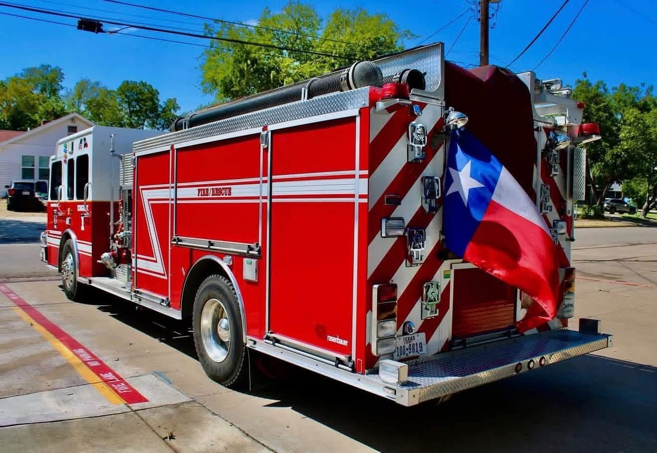 The rear of Engine 1 with red and white chevrons and a Texas flag flying from the back